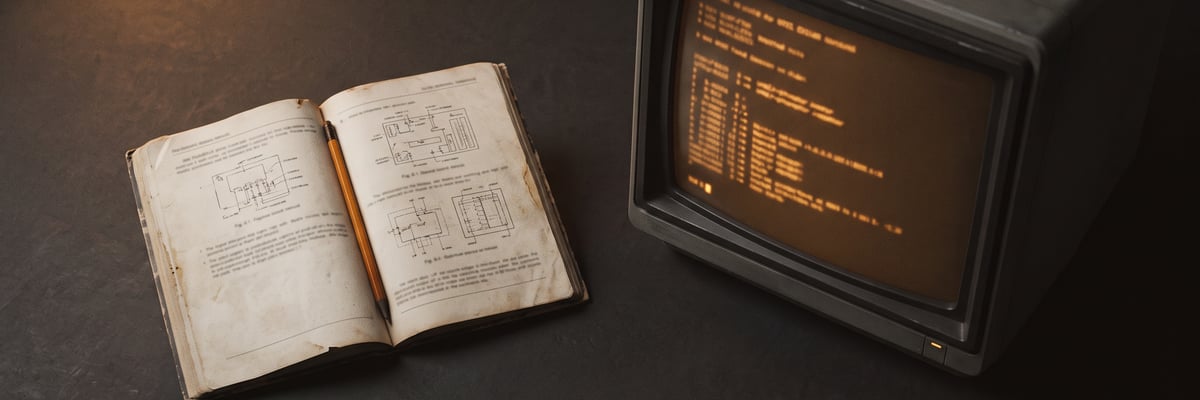 A field notebook beside an amber-phosphor terminal